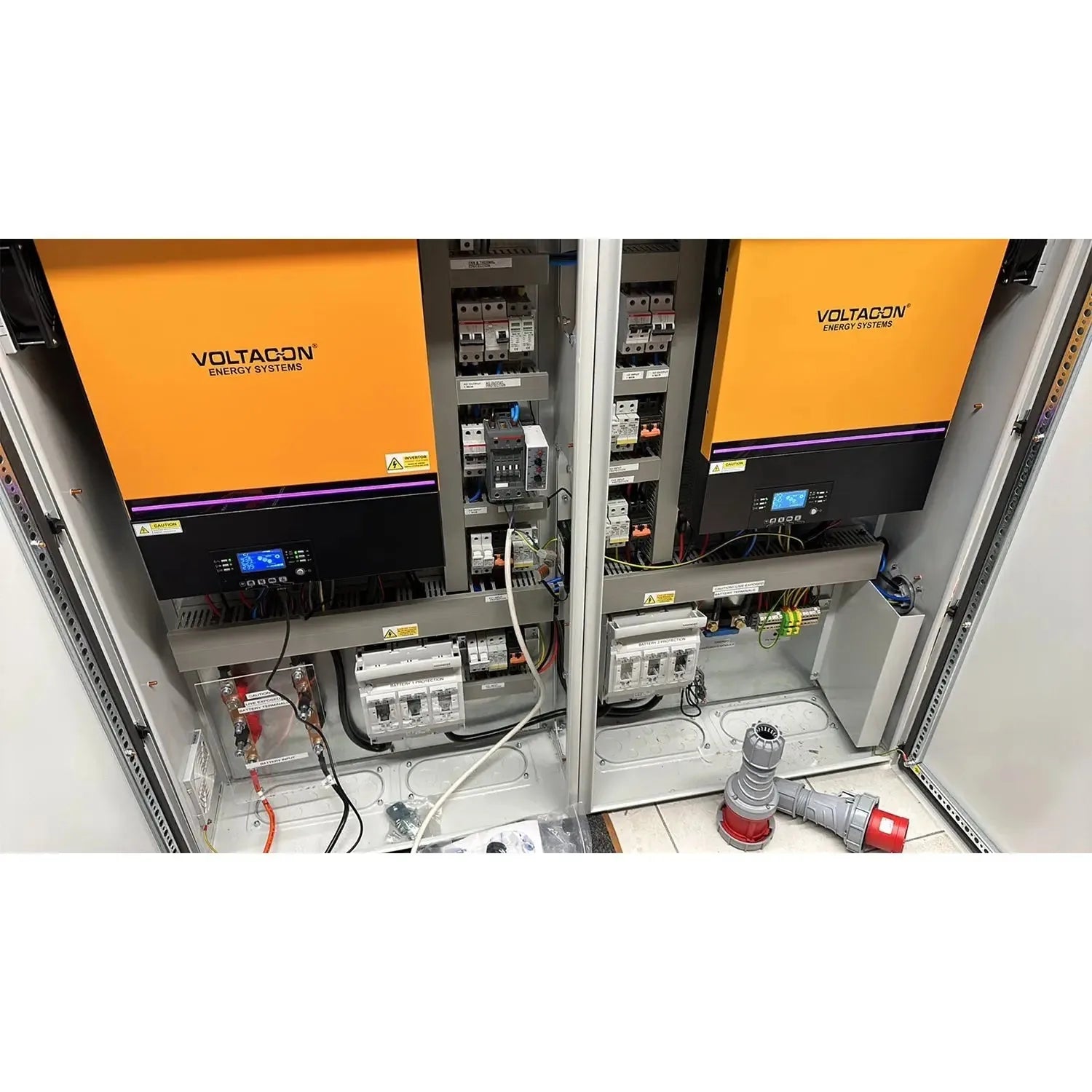 Voltacon Energy Systems off-grid solar control cabinet installation shot showing dual orange-paneled units with internal circ
