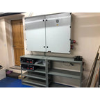 16kW off-grid solar control cabinet installed on wall above metal shelving with electronic equipment, wooden door and blue fl
