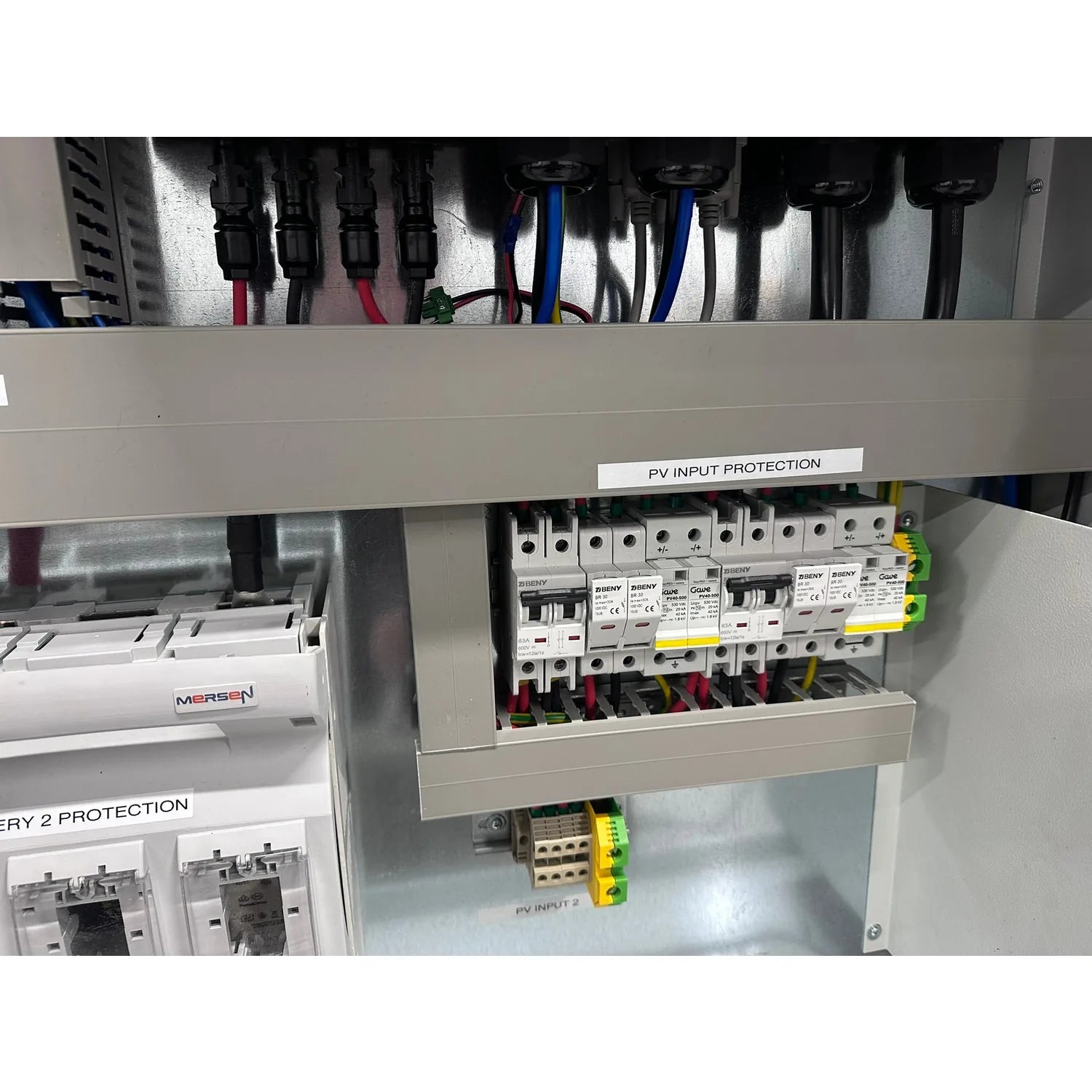 Interior installation shot of solar control cabinet showing PV input protection section with circuit breakers and yellow-gree