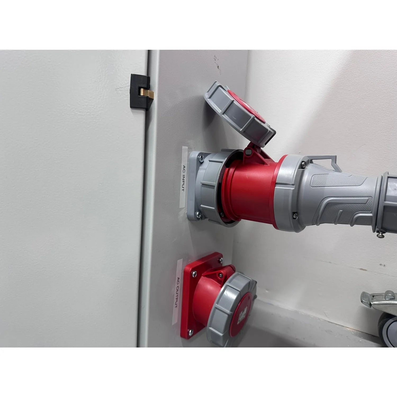 Installation shot showing red and gray industrial electrical connectors mounted on white panel with circuit breaker switch ab
