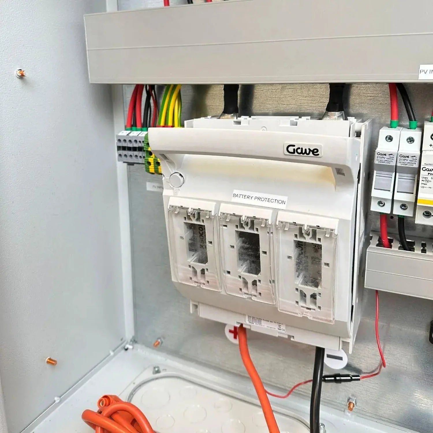 Gawé battery protection module installed in electrical cabinet with colorful wiring and circuit breakers visible.