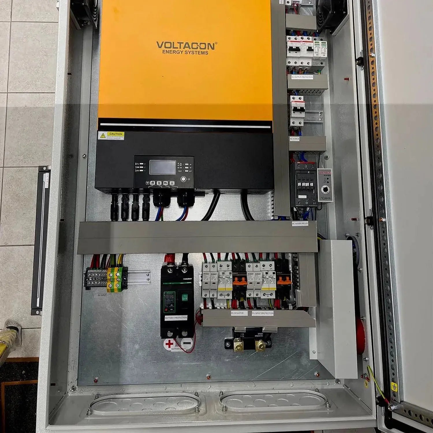Voltacon Energy Systems inverter cabinet installation showing yellow and black case with control display, circuit breakers, a