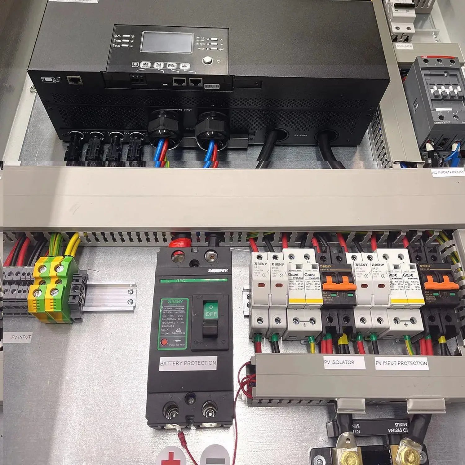 Electrical cabinet interior showing inverter, circuit breakers, battery protection module, PV isolator, and color-coded wirin