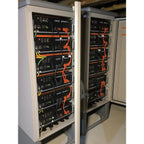 Stacked battery enclosure cabinet with six Pylontech US5000 units mounted vertically, orange and yellow cables visible, insta