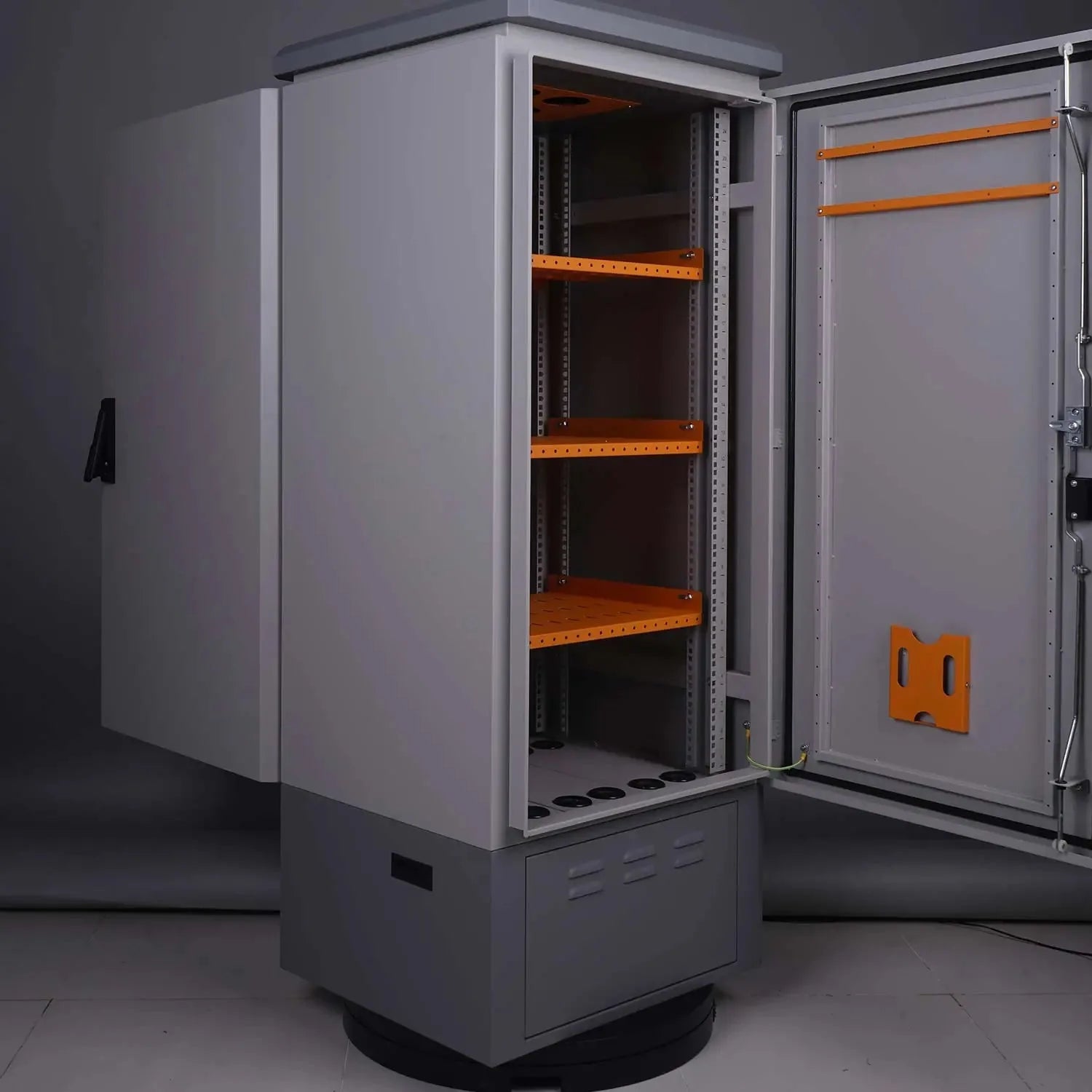 Open industrial battery enclosure with orange metal shelving and cable management ports, showing interior storage capacity
