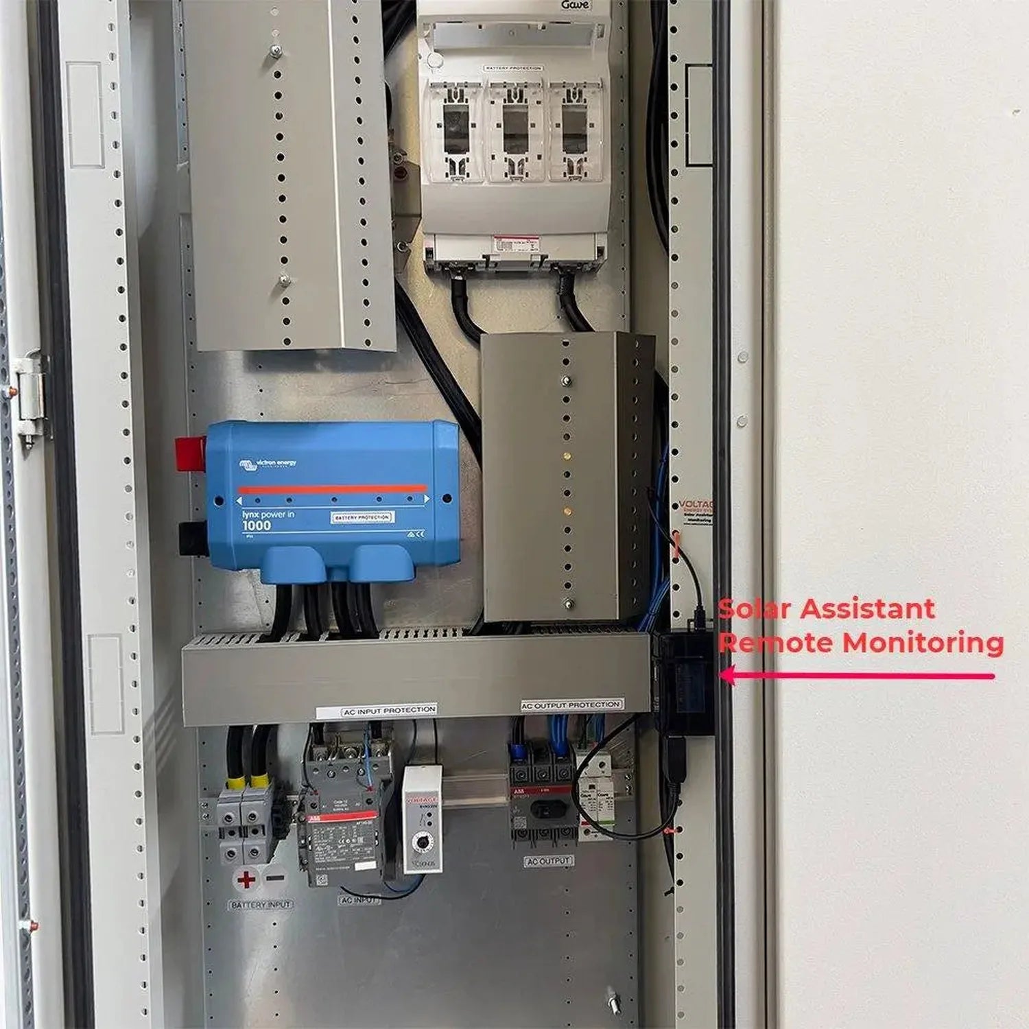Interior of 33kW floor-mounted power cabinet showing blue Victron inverter, circuit breakers, and wiring with Solar Assistant