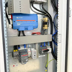 Interior installation view of floor-mounted power cabinet showing blue Victron Lynx Power In 1000 inverter, battery terminals