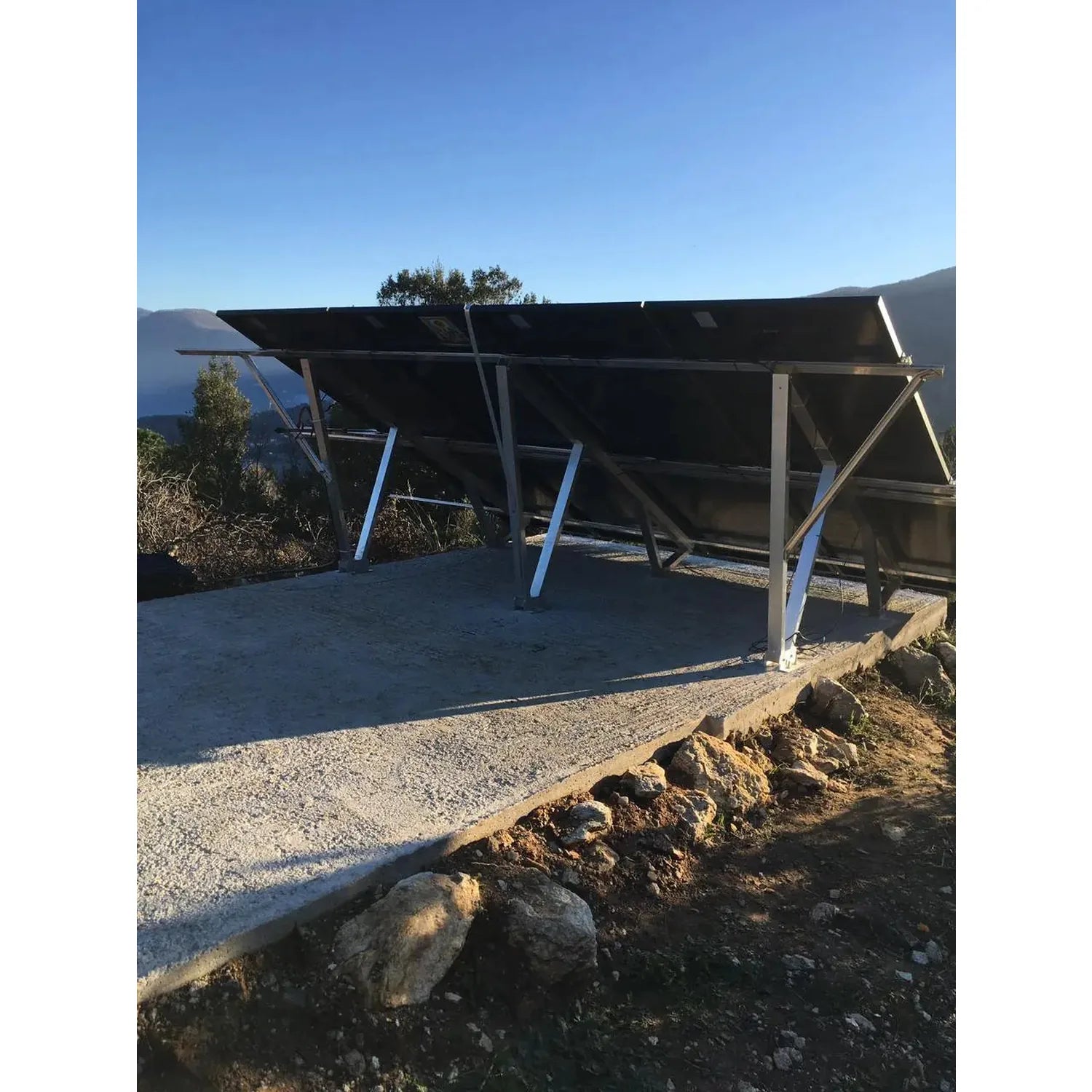 Solar panel installation shot showing black half-cut monocrystalline panels mounted on metal frame structure in mountainous o