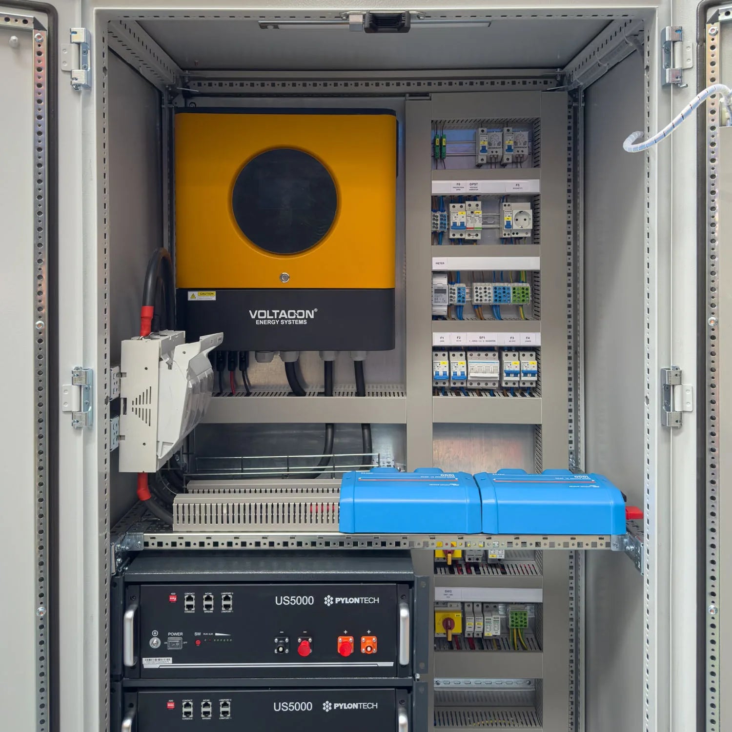 Installation shot of Voltacon off-grid power cabinet with yellow Voltagon inverter, blue battery modules, dual Pylontech US50